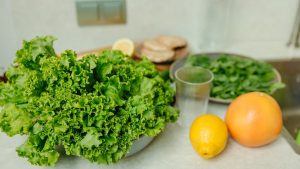 A vibrant display of fresh green lettuce and citrus fruits on a kitchen table.